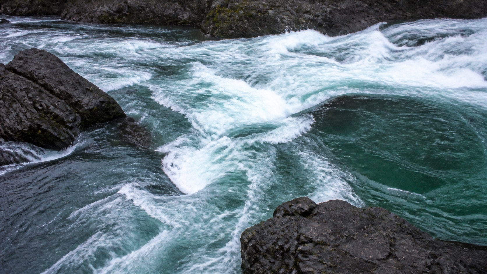 Visible current tongues, eddy seams, and waves around basalt rocks